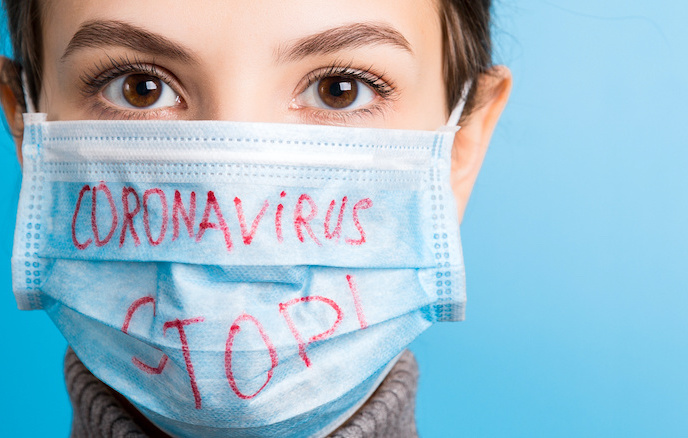 Portrait of a woman in medical mask with stop coronavirus text at blue background. Coronavirus concept. Respiratory protection Portrait of a woman in medical mask with stop coronavirus text at blue background. Coronavirus concept. Respiratory protection.