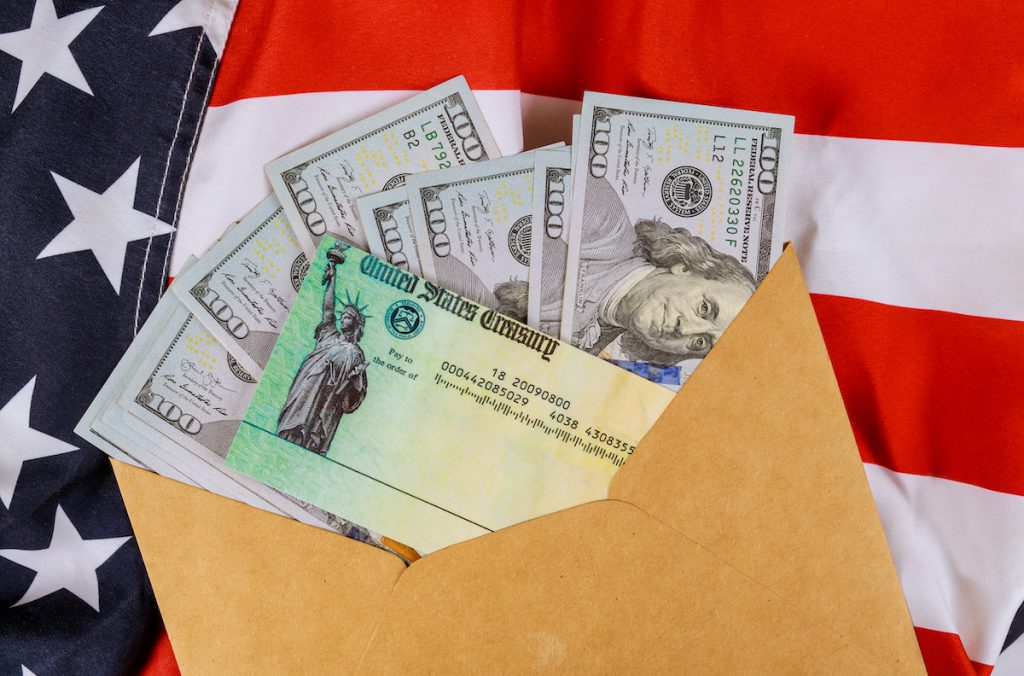 Senate stimulus deal includes individual checks virus economic stimulus plan US 100 dollar bills currency on American flag Global pandemic Covid 19 lockdown Senate stimulus deal includes individual checks virus economic stimulus plan USA dollar cash banknote on American flag Global pandemic Covid 19 lockdown