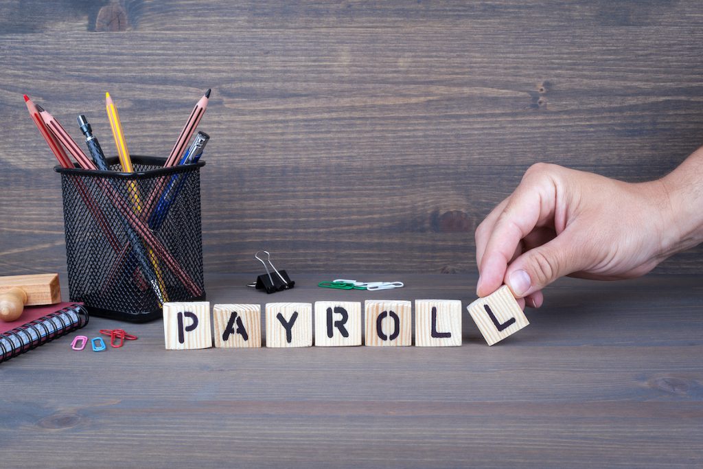 payroll. Wooden letters on dark background payroll concept. Wooden letters on dark background